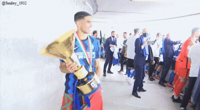 A Man Holding A Trophy In A Locker Room With A Smiley 1932 Watermark GIF