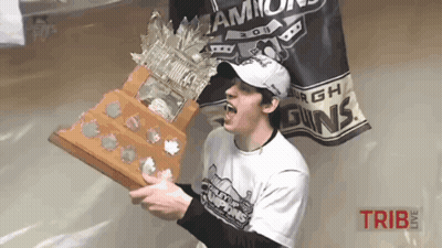 A Man Holding A Trophy In Front Of A Banner That Says ' Champs ' On It GIF