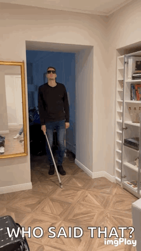 A Man Holding A White Cane In A Hallway With The Caption Who Said That GIF