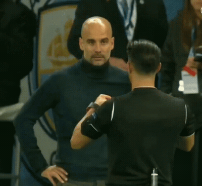 A Man Holding A Yellow Card In Front Of An Anchester Logo GIF