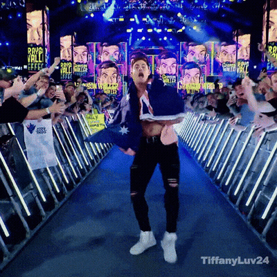 A Man Holding An Australian Flag Walks Down A Blue Aisle Surrounded By Fans GIF