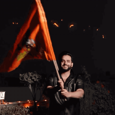 A Man Holding An Orange Flag In Front Of A Sign That Says ' I ' On It GIF