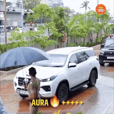 A Man Holding An Umbrella In Front Of A Car That Says Aura On The Bottom GIF