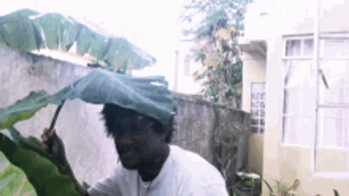 A Man Holding An Umbrella Over His Head GIF