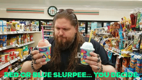 A Man Holding Two Cups Of Slurpee In A Convenience Store GIF