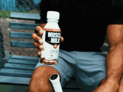 A Man Holds A Bottle Of Muscle Milk In His Hand GIF