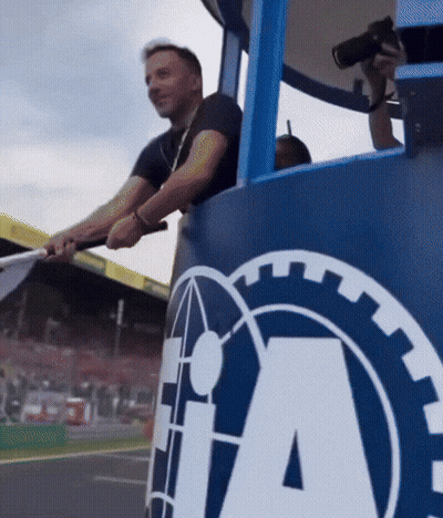 A Man Holds A Flag In Front Of A Large Ia Logo GIF