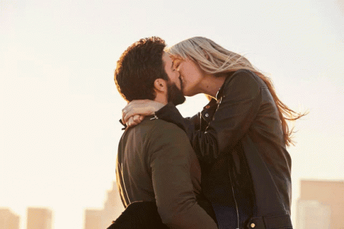 A Man Holds A Woman In His Arms And They Kiss GIF