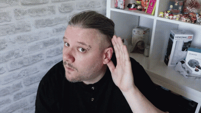 A Man Holds His Hand To His Ear In Front Of A Box That Says Videomic GIF