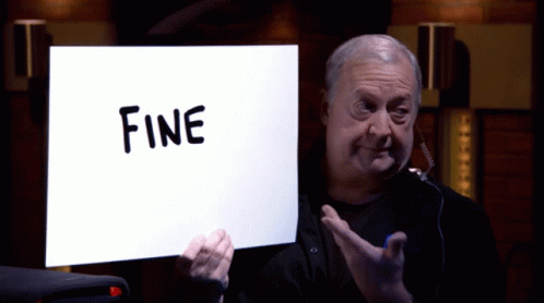 A Man Holds Up A Sign That Says Fine On It GIF