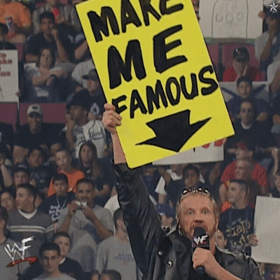 A Man Holds Up A Yellow Sign That Says Make Me Famous GIF