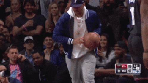 A Man In A Baseball Cap Holds A Basketball In Front Of A Crowd With The Number 1 On His Jersey GIF