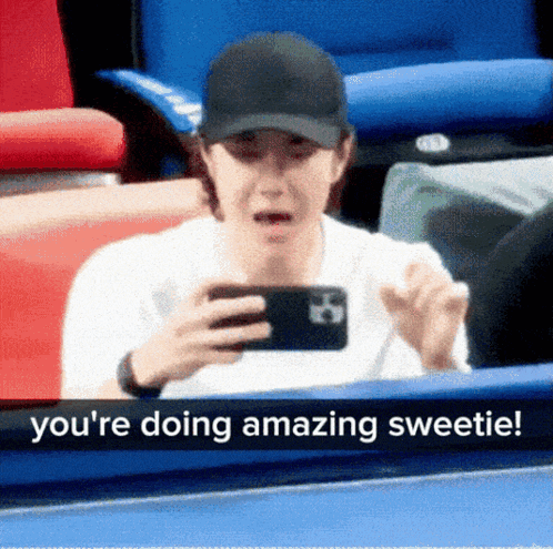 A Man In A Baseball Cap Is Looking At His Phone And Says " You 'Re Doing Amazing Sweetie ! " GIF