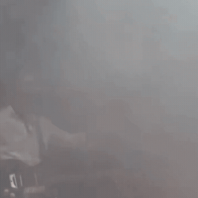 A Man In A Baseball Cap Is Playing A Guitar On Stage GIF