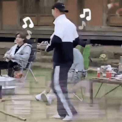 A Man In A Baseball Cap Is Standing In Front Of A Group Of People Sitting In Chairs And A Table . GIF