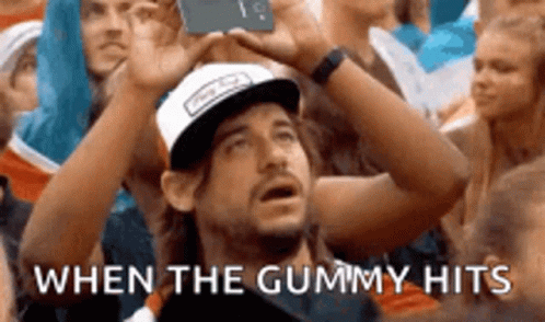 A Man In A Baseball Cap Is Taking A Picture Of A Crowd Of People . GIF
