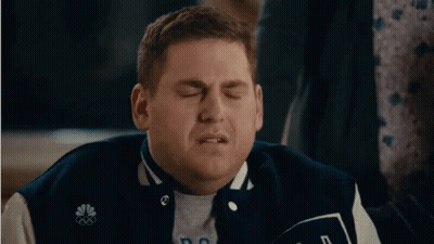 A Man In A Baseball Jacket Is Making A Funny Face . GIF