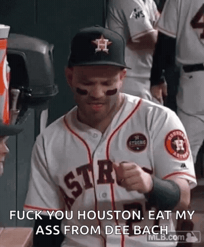 A Man In A Baseball Uniform Is Sitting In A Dugout And Talking To Someone . GIF