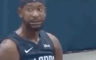A Man In A Basketball Jersey Is Looking At The Camera . GIF