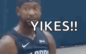 A Man In A Basketball Jersey Is Standing In Front Of A Blue Wall With The Words Yikes ! Written On It . GIF