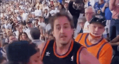 A Man In A Basketball Jersey Is Standing In Front Of A Crowd Of People In A Stadium . GIF