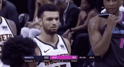 A Man In A Basketball Uniform Is Standing In Front Of A Crowd During A Basketball Game . GIF