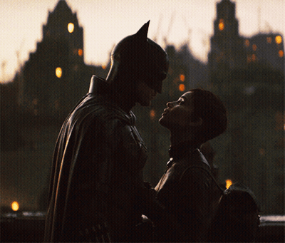 A Man In A Bat Suit And A Woman In A Catsuit Are Looking Into Each Other 'S Eyes GIF