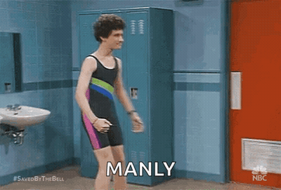 A Man In A Bathing Suit Is Standing In A Locker Room And Saying `` Manly '' . GIF