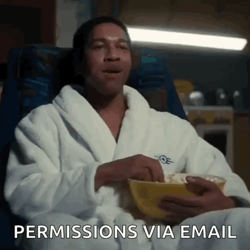 A Man In A Bathrobe Is Sitting In A Chair Eating Popcorn And Says Permission Via Email GIF