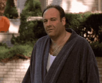 A Man In A Bathrobe Stands In Front Of A House GIF