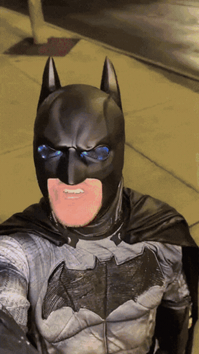 A Man In A Batman Costume Is Smiling GIF