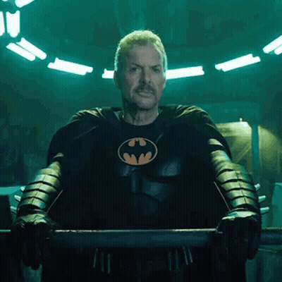 A Man In A Batman Costume Is Standing In A Dark Room . GIF