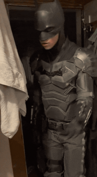 A Man In A Batman Costume Is Standing Next To A Towel GIF