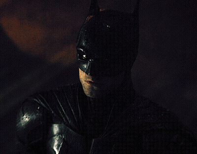 A Man In A Batman Costume Looks At The Camera GIF