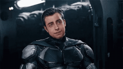 A Man In A Batman Suit Is Sitting Down With His Eyes Closed And Smiling . GIF