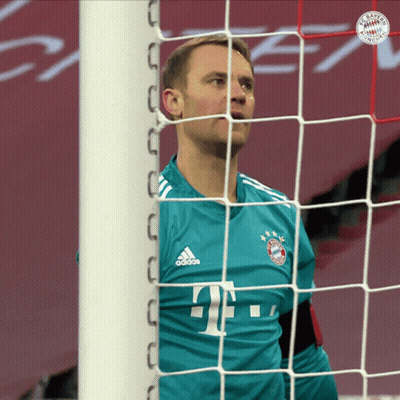 A Man In A Bayern Munich Jersey Stands In Front Of A Soccer Net GIF