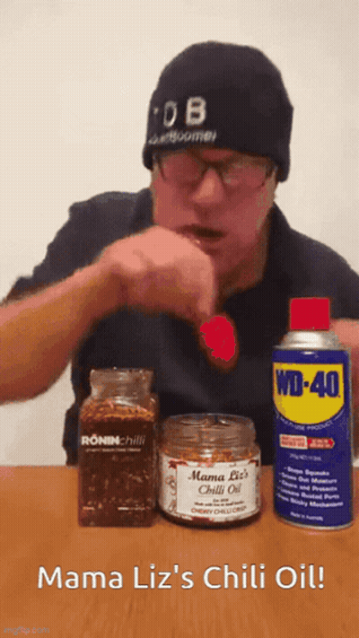 A Man In A Beanie Is Eating A Red Pepper Next To A Can Of Wd-40 GIF