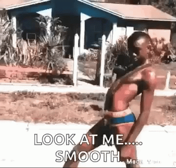 A Man In A Bikini Is Walking Down A Sidewalk With The Words `` Look At Me Smooth '' Written On It . GIF