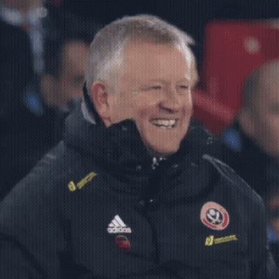 A Man In A Black Adidas Jacket Is Standing In Front Of A Crowd . GIF