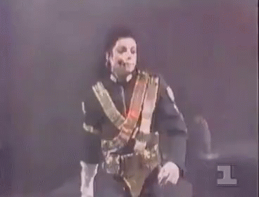 A Man In A Black And Gold Uniform Is Standing In Front Of A Red Background With The Number 1 On It GIF