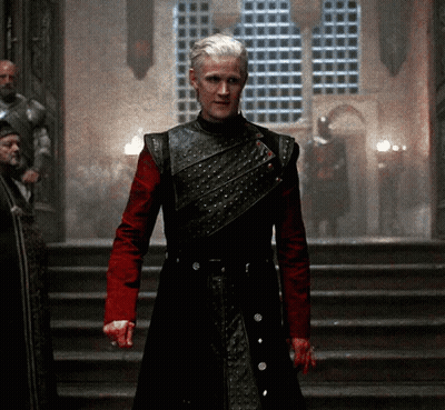 A Man In A Black And Red Armor Stands On Stairs GIF