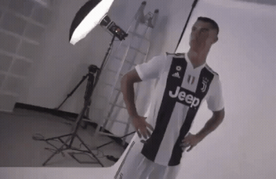 A Man In A Black And White Jeep Jersey Is Standing In Front Of A Light . GIF