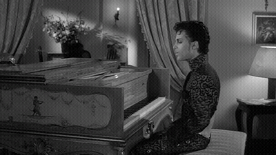 A Man In A Black And White Photo Is Playing A Piano GIF