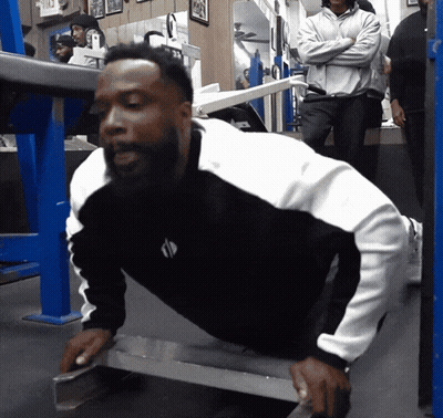 A Man In A Black And White Shirt Is Doing Push Ups On A Bench GIF