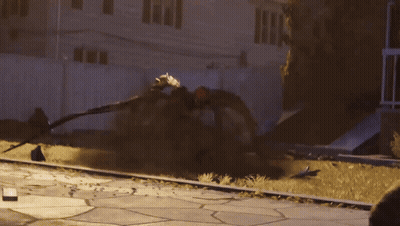 A Man In A Black And White Spiderman Costume Is Standing In Front Of A Building GIF