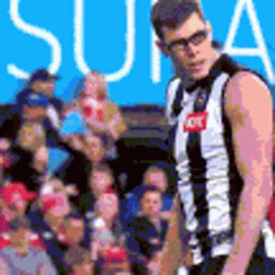 A Man In A Black And White Striped Jersey Is Standing In Front Of A Crowd Of People . GIF
