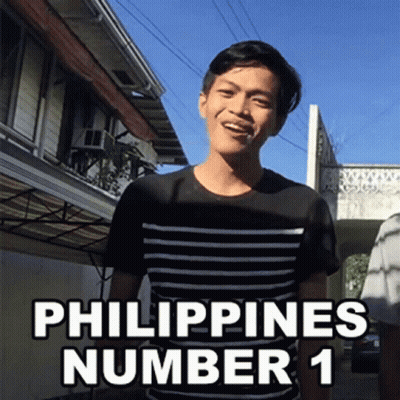 A Man In A Black And White Striped Shirt Is Standing In Front Of A Building With The Words Philippines Number 1 Written  GIF