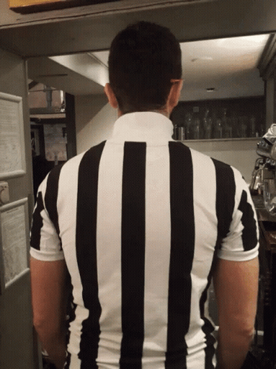 A Man In A Black And White Striped Shirt Stands In A Kitchen GIF