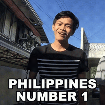 A Man In A Black And White Striped Shirt Stands In Front Of A Building With The Words Philippines Number 1 Above Him GIF