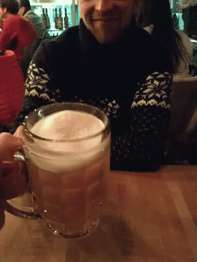 A Man In A Black And White Sweater Holds A Glass Of Beer GIF